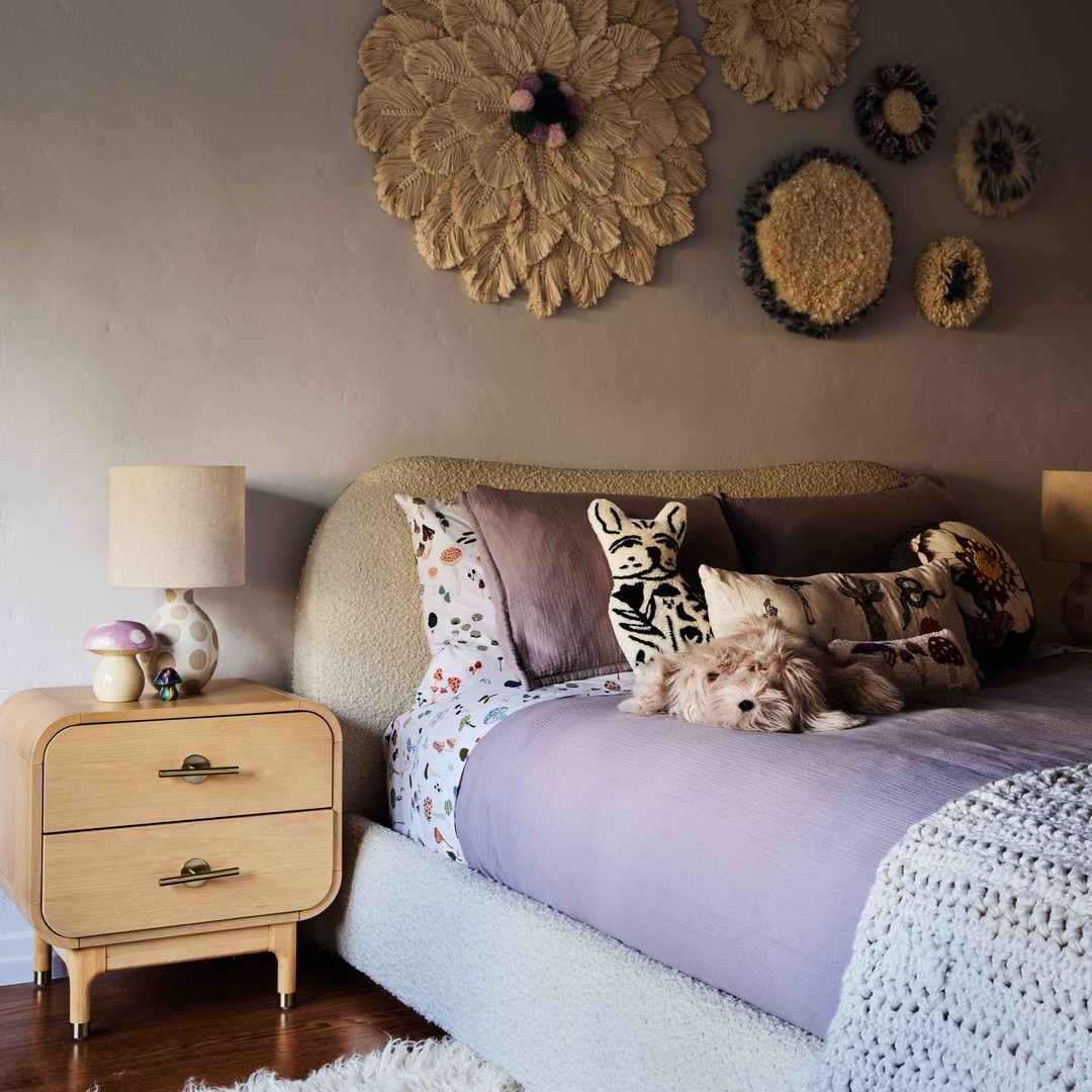 a bedroom with a bed, nightstand, and wall hangings