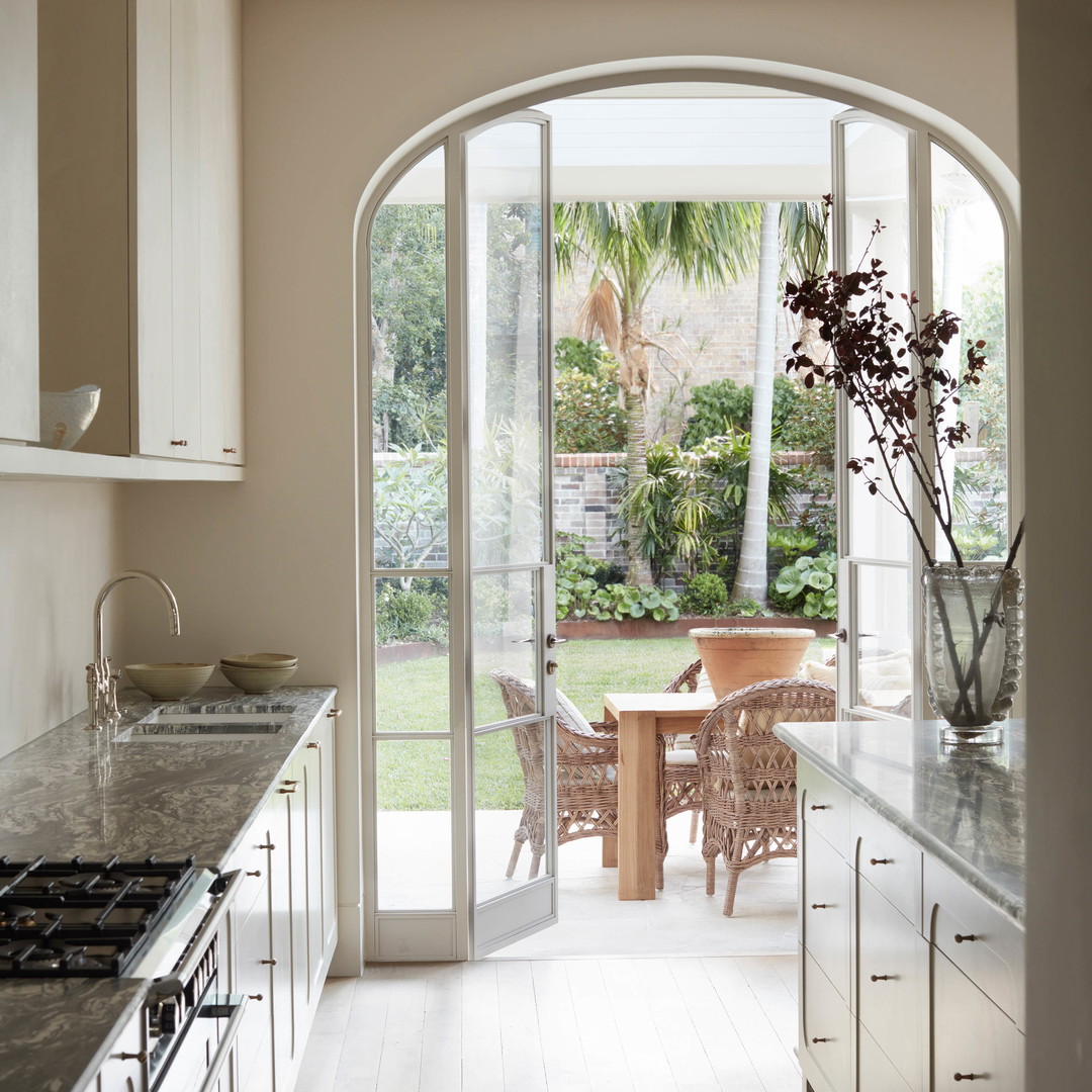 a kitchen with an arched glass door leading to a dining area