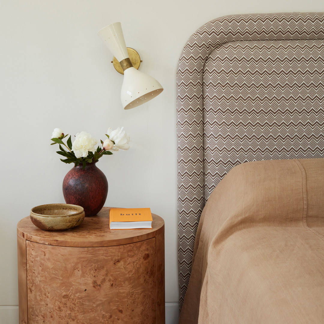 a nightstand with a lamp and a vase with flowers on it