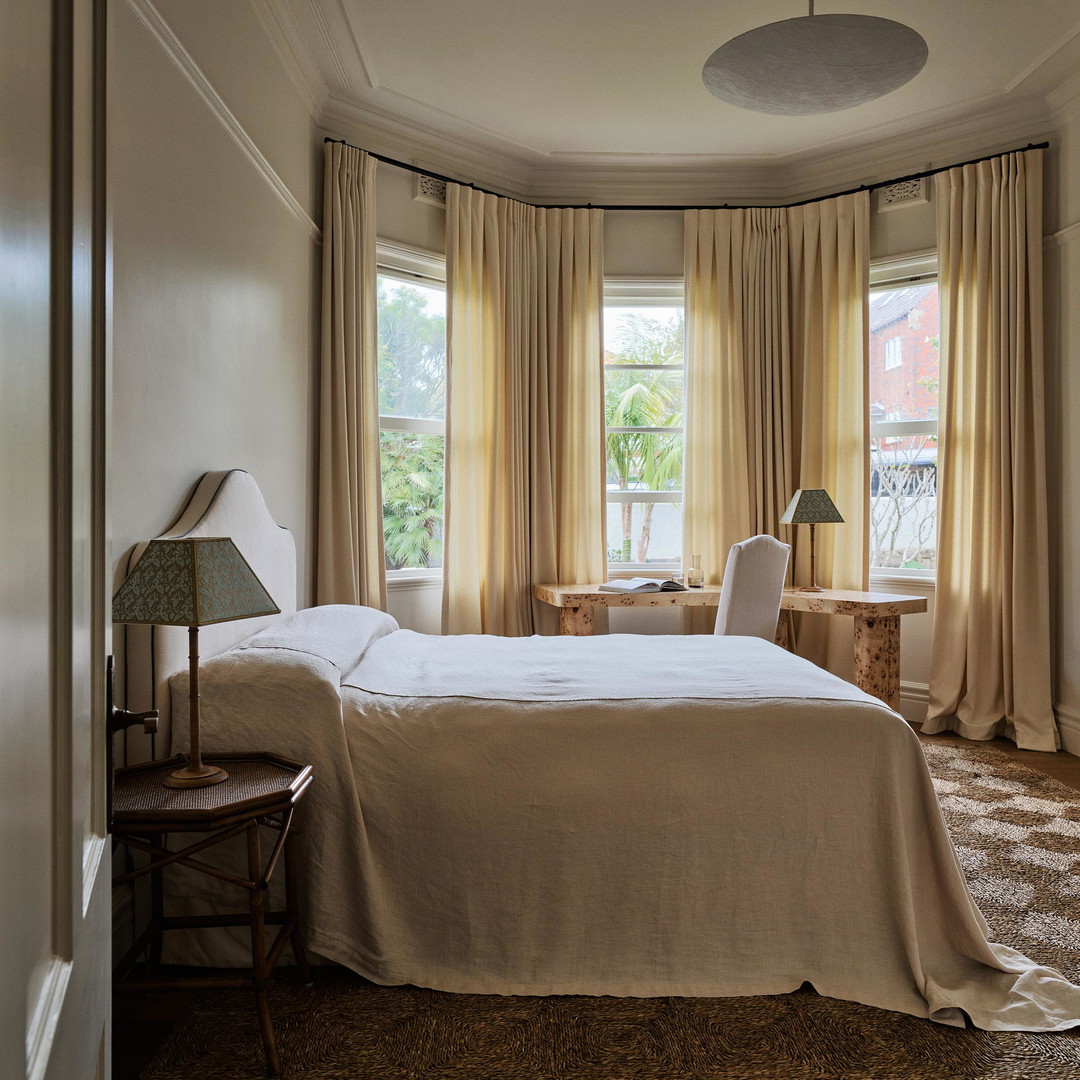 a bedroom with a large bed and two windows