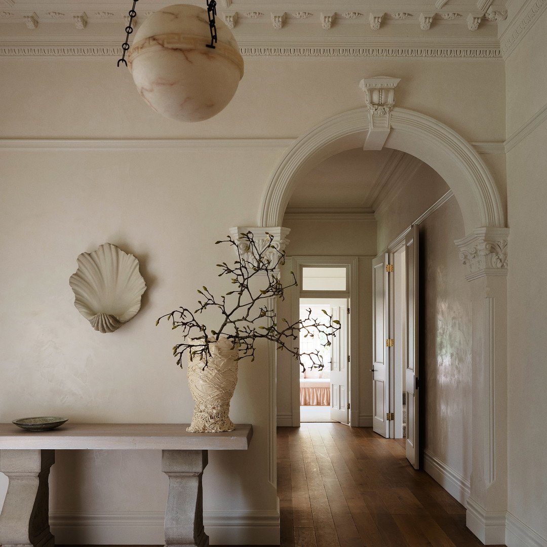 a hallway with a bench and a vase of flowers