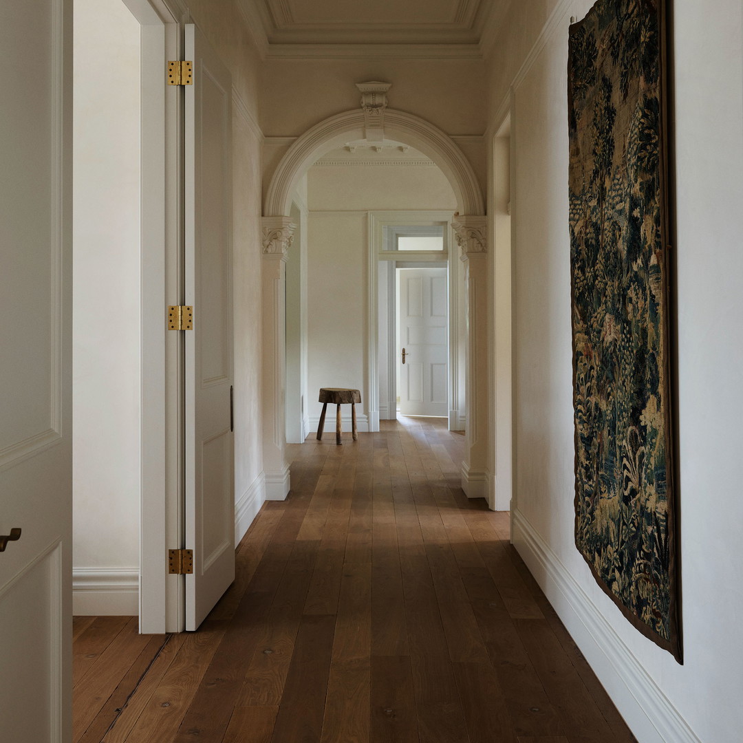 a long hallway with a bench and a tapestry on the wall