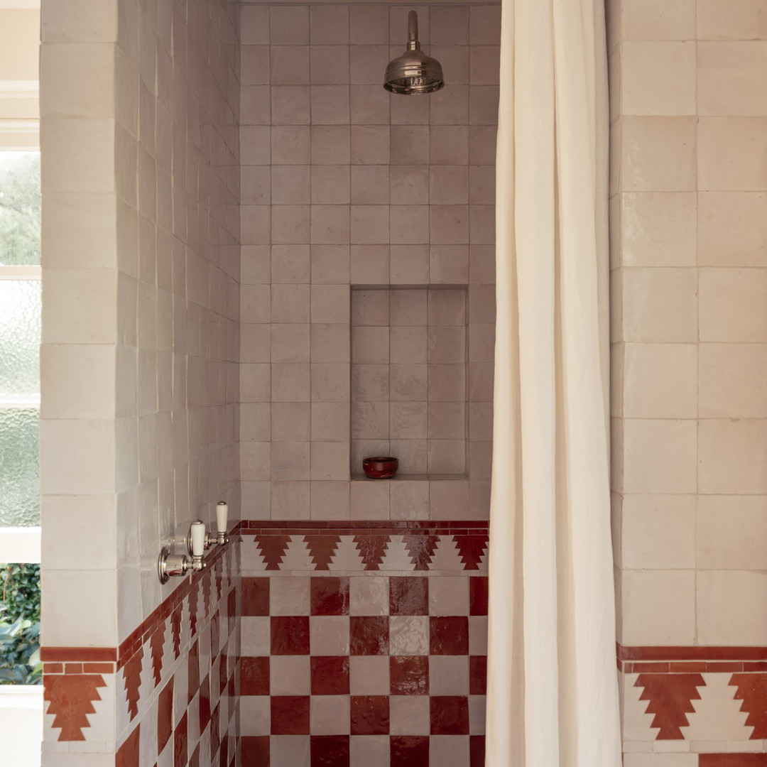 a bathroom with red and white tiles and a shower