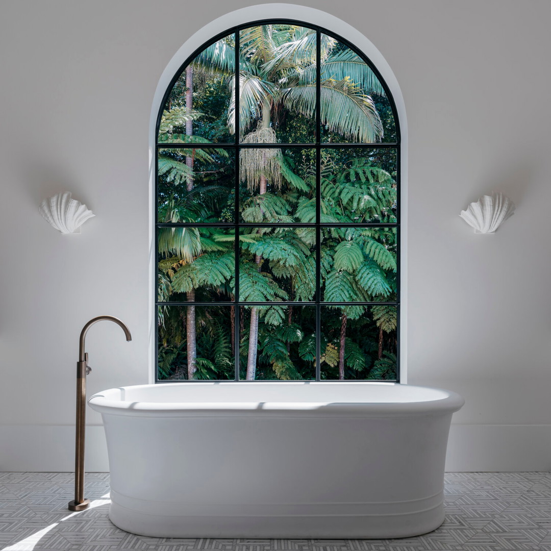 a white bath tub sitting under a large window