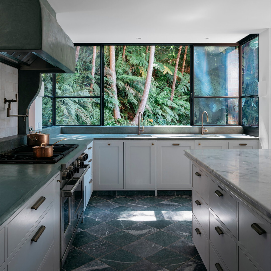 a kitchen with a large window overlooking a forest