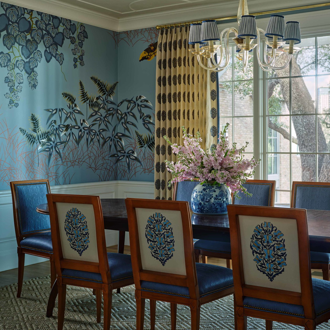 a dining room table with blue chairs and a vase of flowers