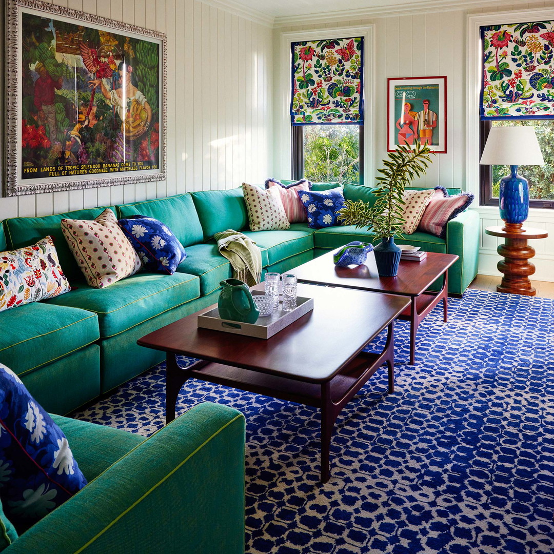 a living room filled with green couches and a blue rug