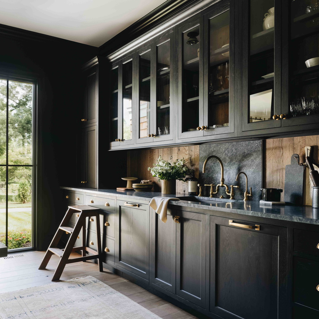 a kitchen with black cabinets and wooden floors