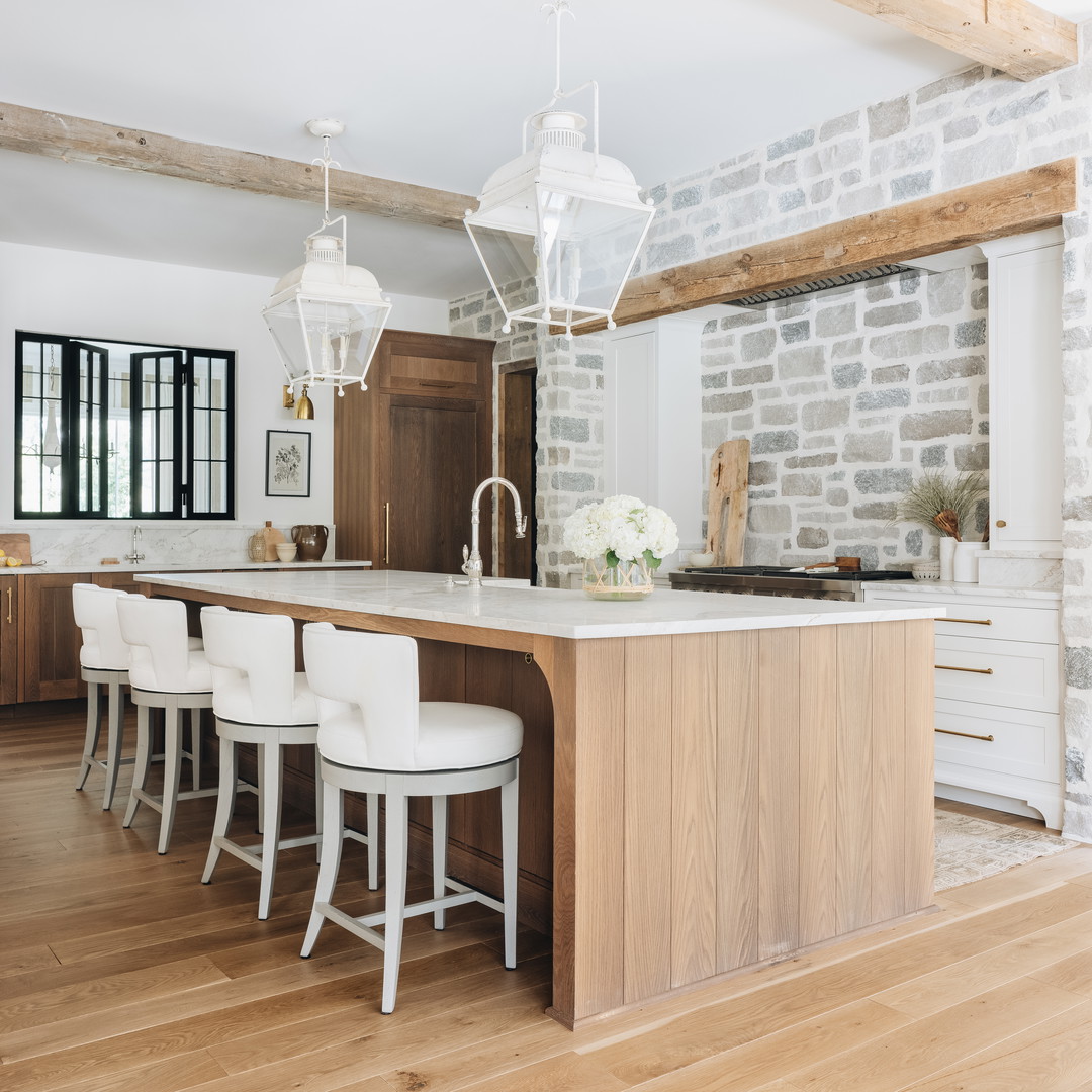 a large kitchen with a center island and white chairs