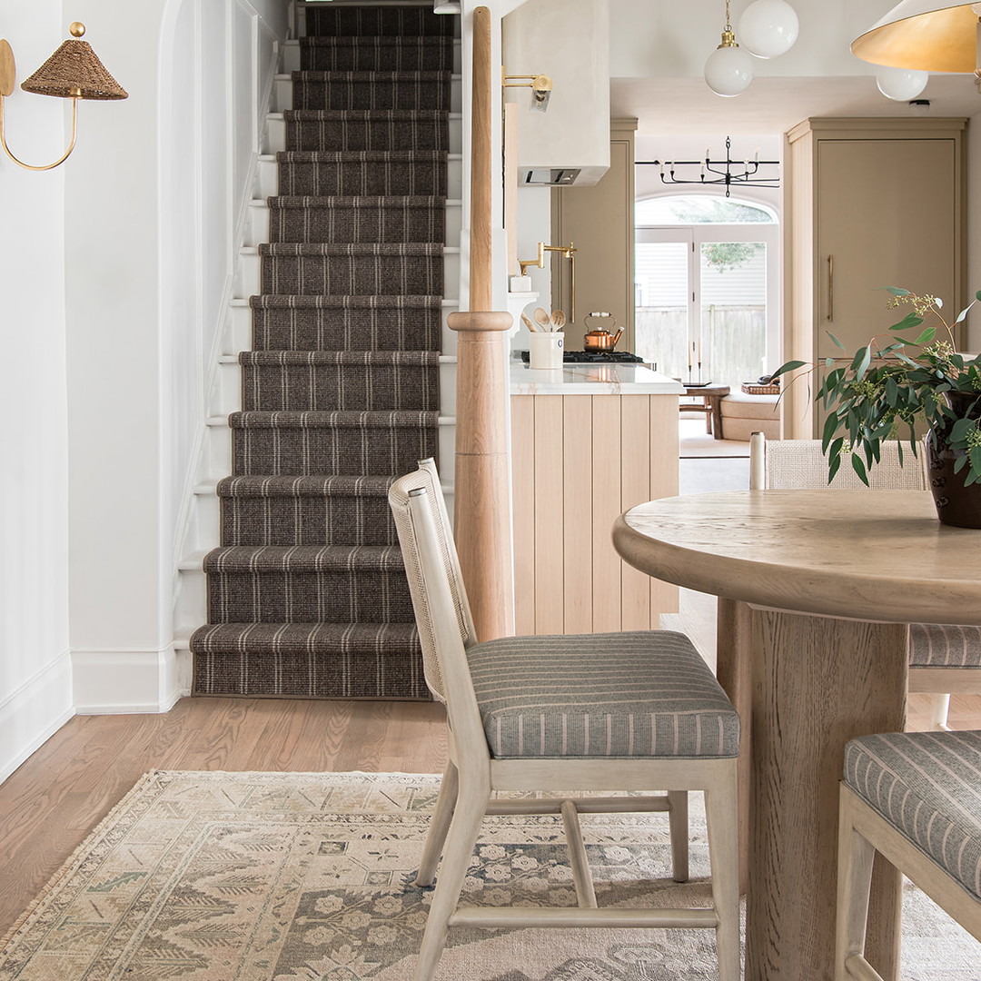 a dining room table with two chairs and a rug on the floor