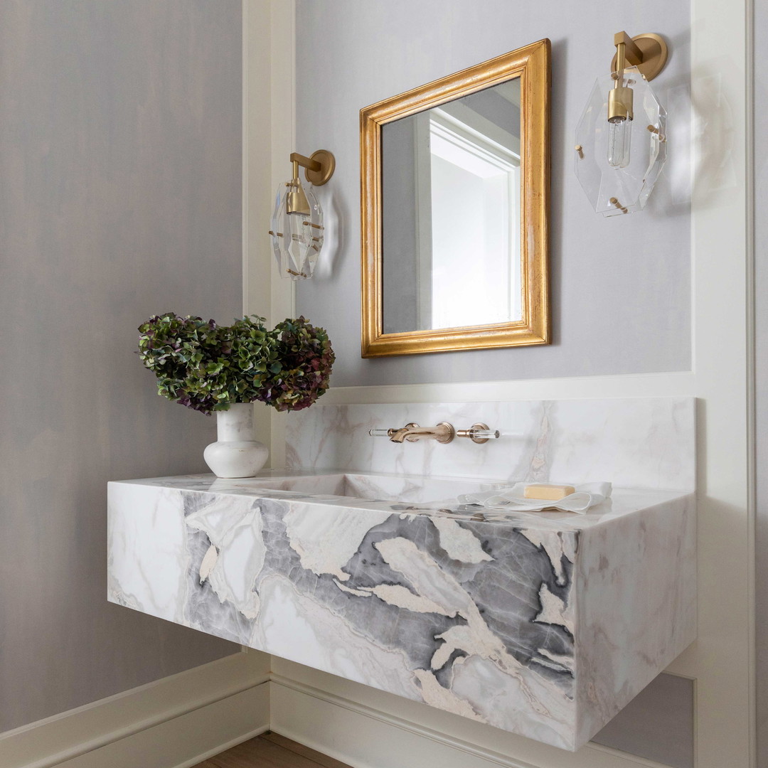 a bathroom with a marble sink and a gold framed mirror