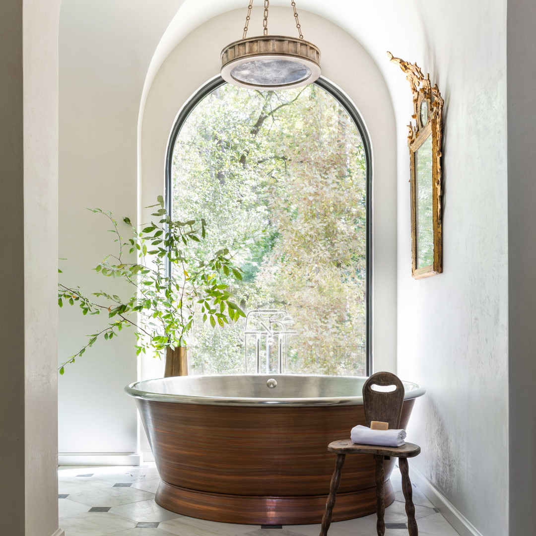 a large bath tub sitting under a window next to a chair