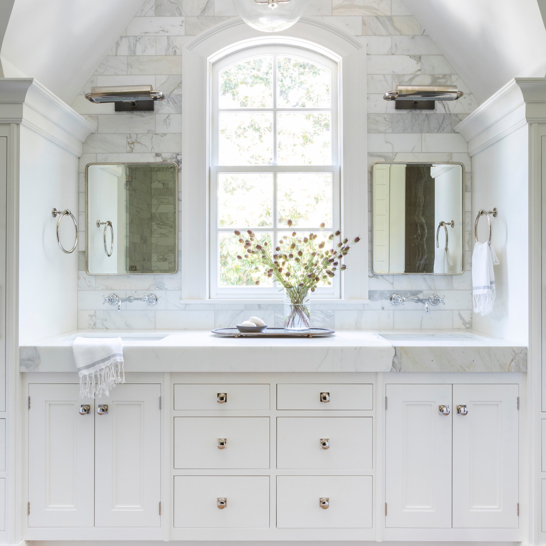 a white bathroom with two sinks and a window