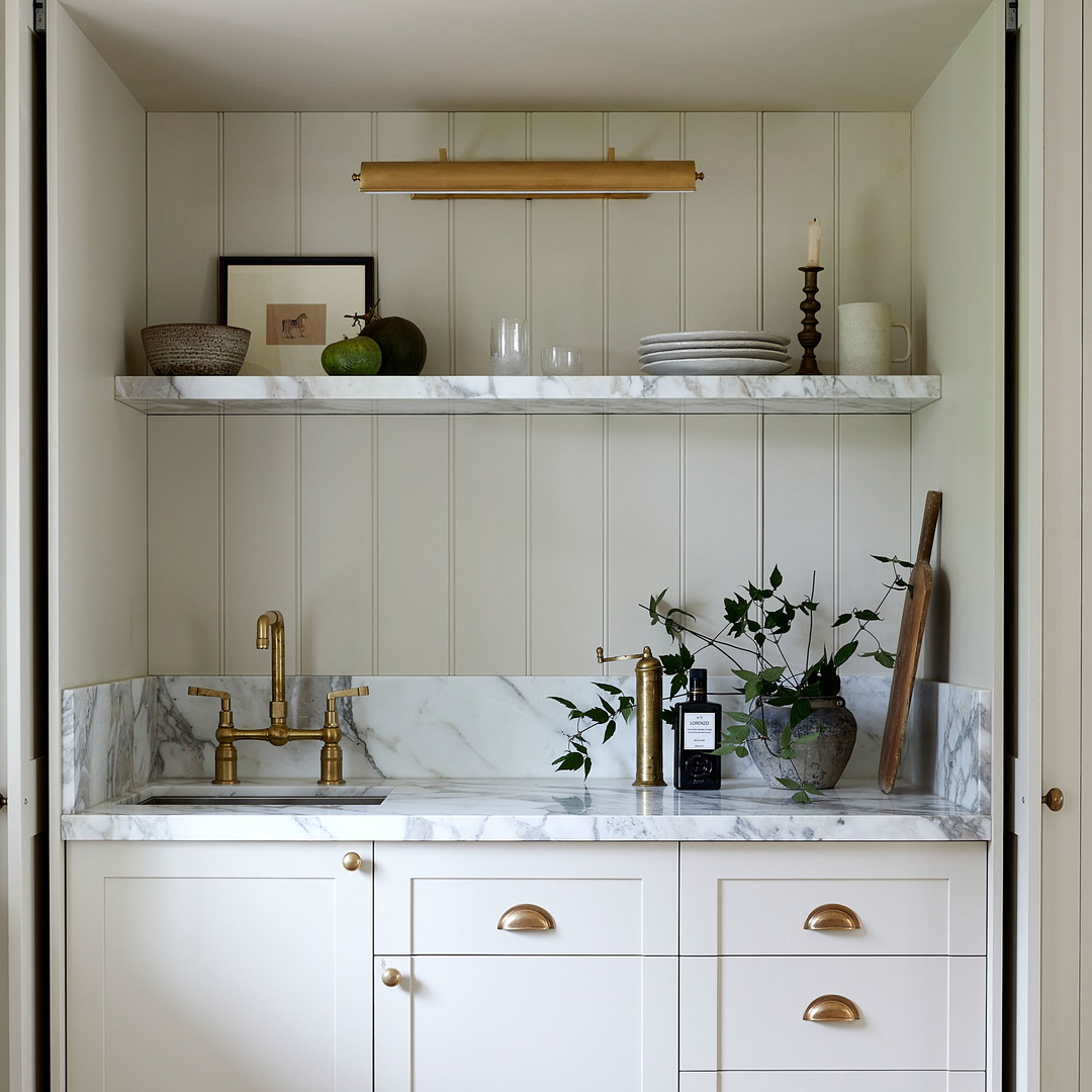 a kitchen with white cabinets and marble counter tops
