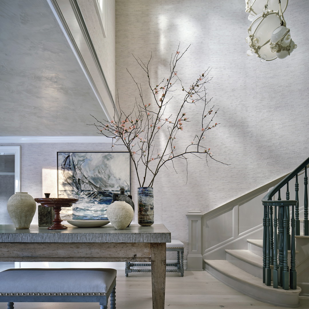 a room with a table, vases and a staircase