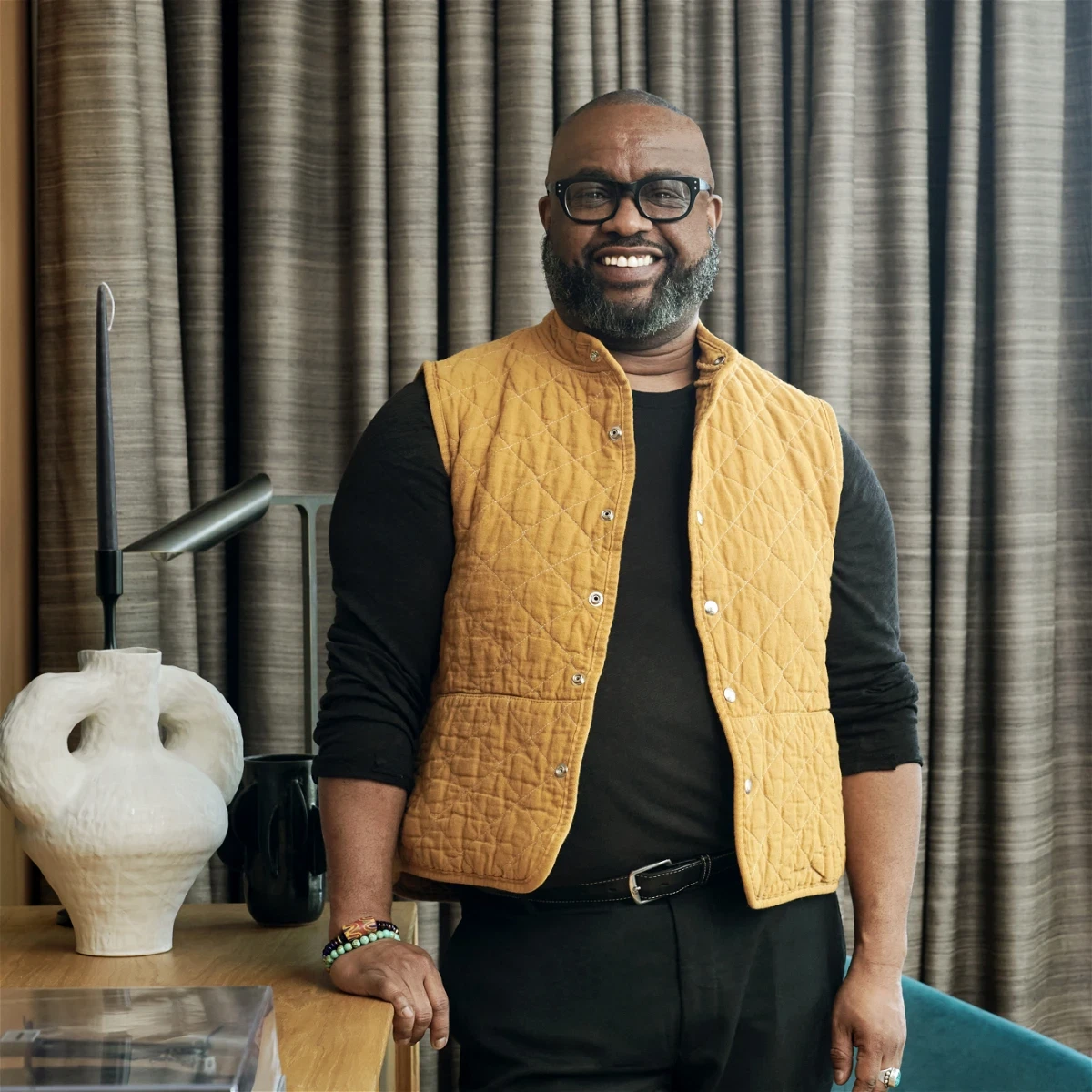 a man in a yellow vest standing in front of a table