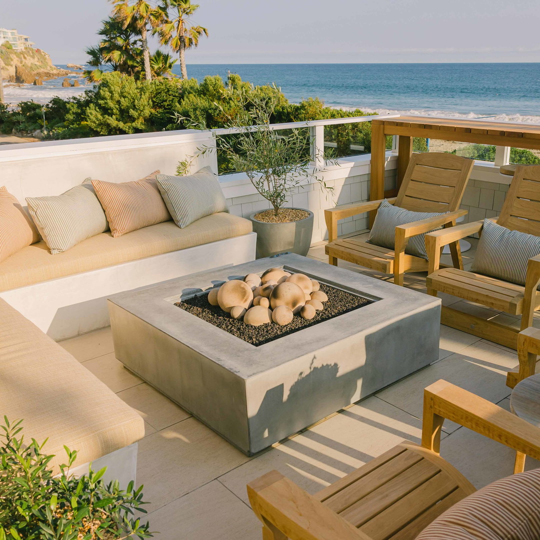 a fire pit sitting on top of a patio next to the ocean