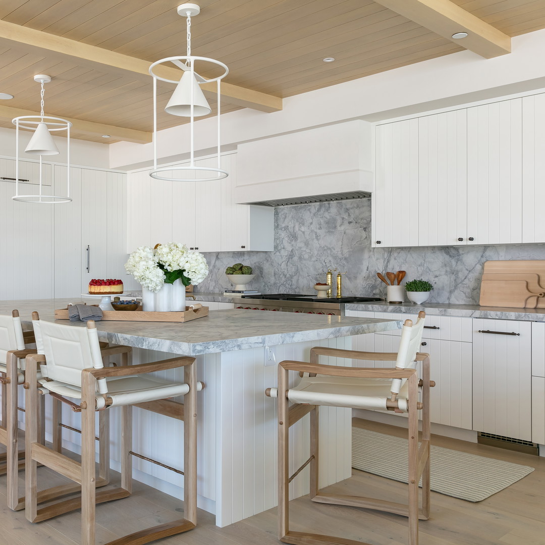 a large kitchen with a center island surrounded by chairs