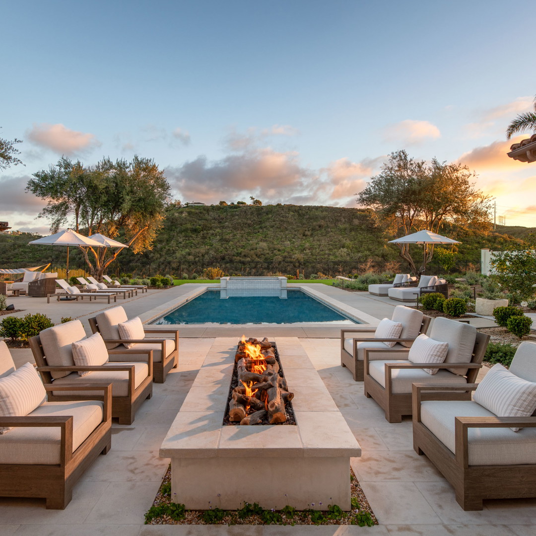 a patio with a fire pit surrounded by lounge chairs