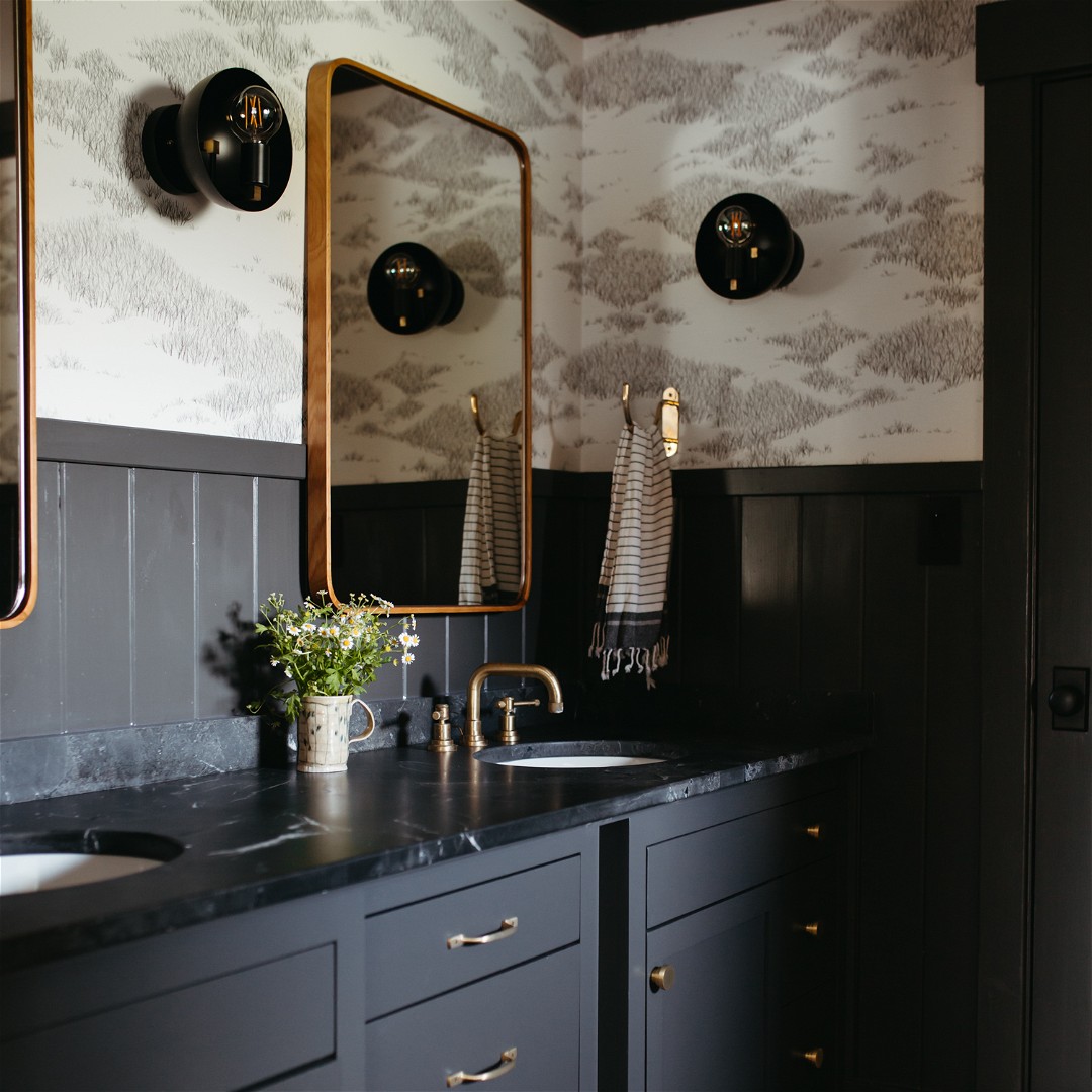 a black and white bathroom with two sinks and mirrors