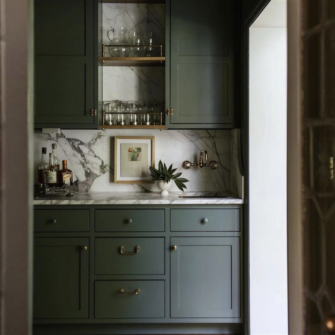a kitchen with green cabinets and marble counter tops