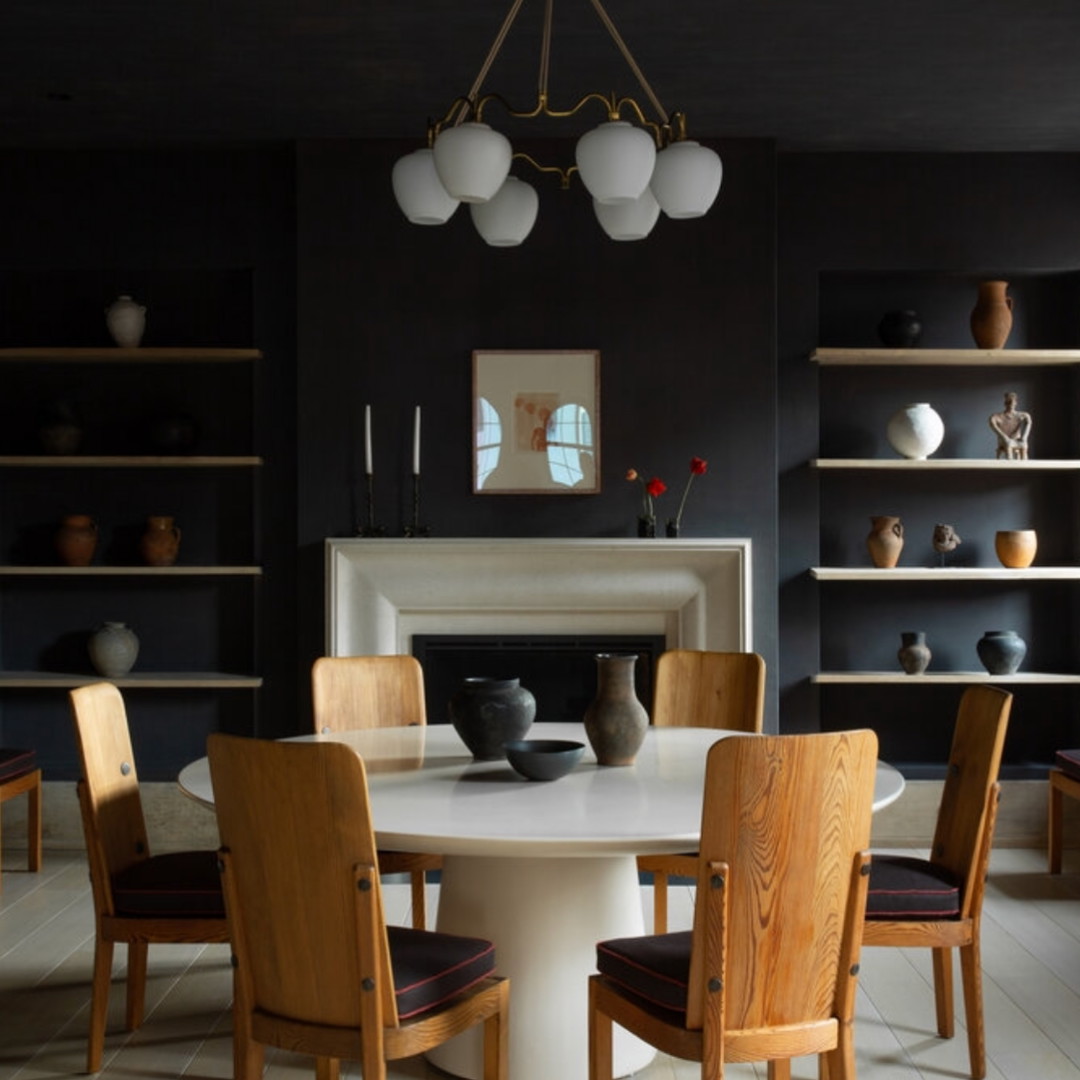 a dining room with a white table surrounded by wooden chairs