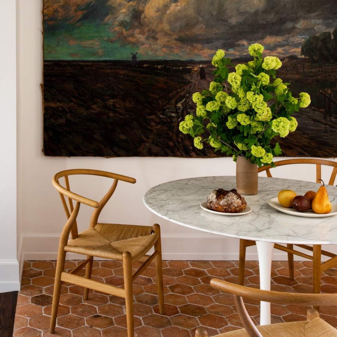 a table with two chairs and a vase with flowers on it