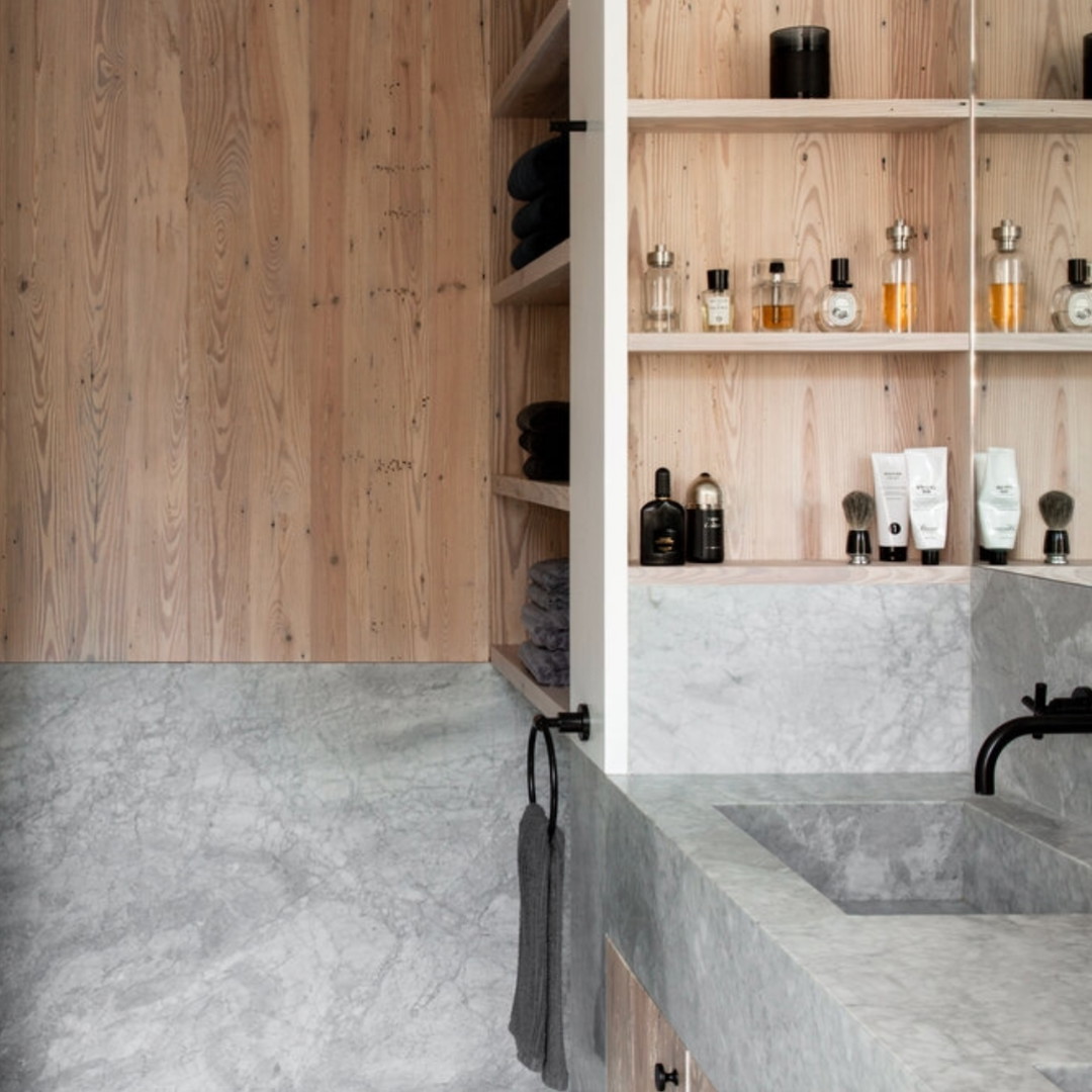 a bathroom with marble counter tops and wooden shelves