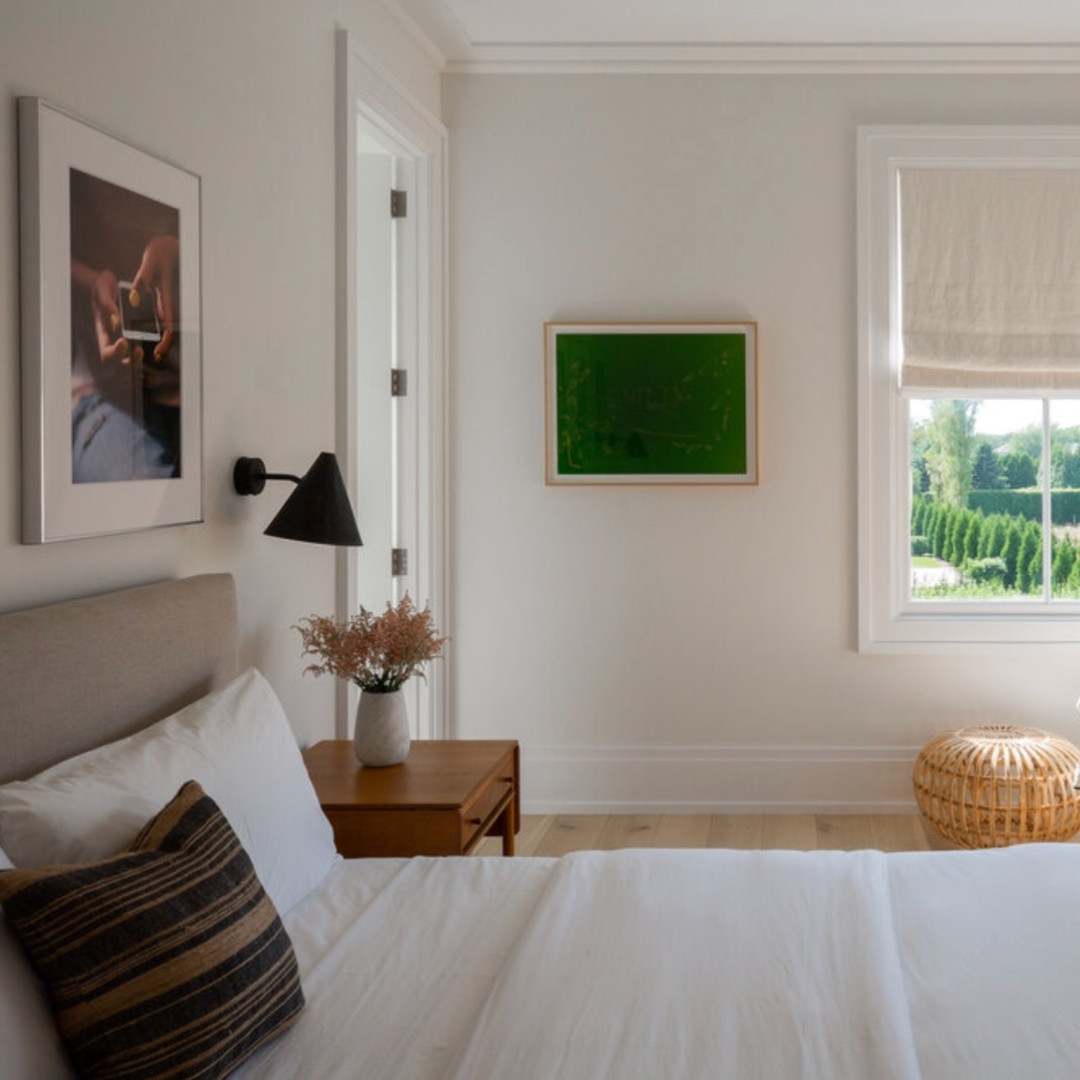 a bedroom with a white bed and a painting on the wall