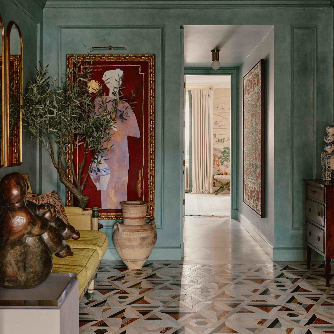 a hallway with a painting on the wall and a vase with a plant in it