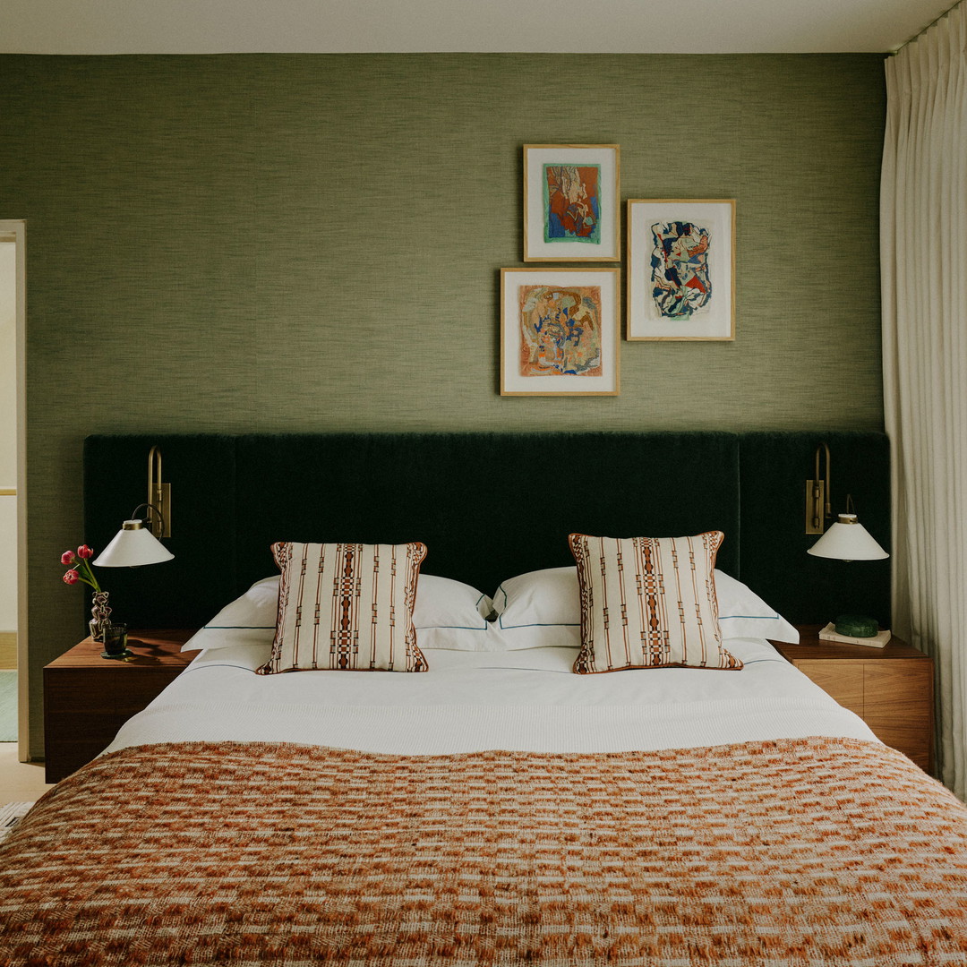 a bedroom with a neatly made bed and pictures on the wall