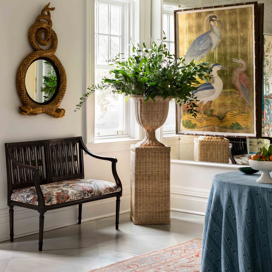 a room with a table, chair, mirror and a painting on the wall