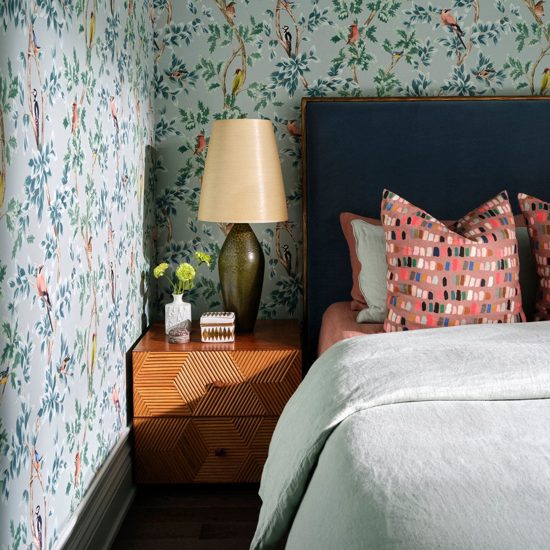 a bedroom with a floral wallpaper and a blue headboard