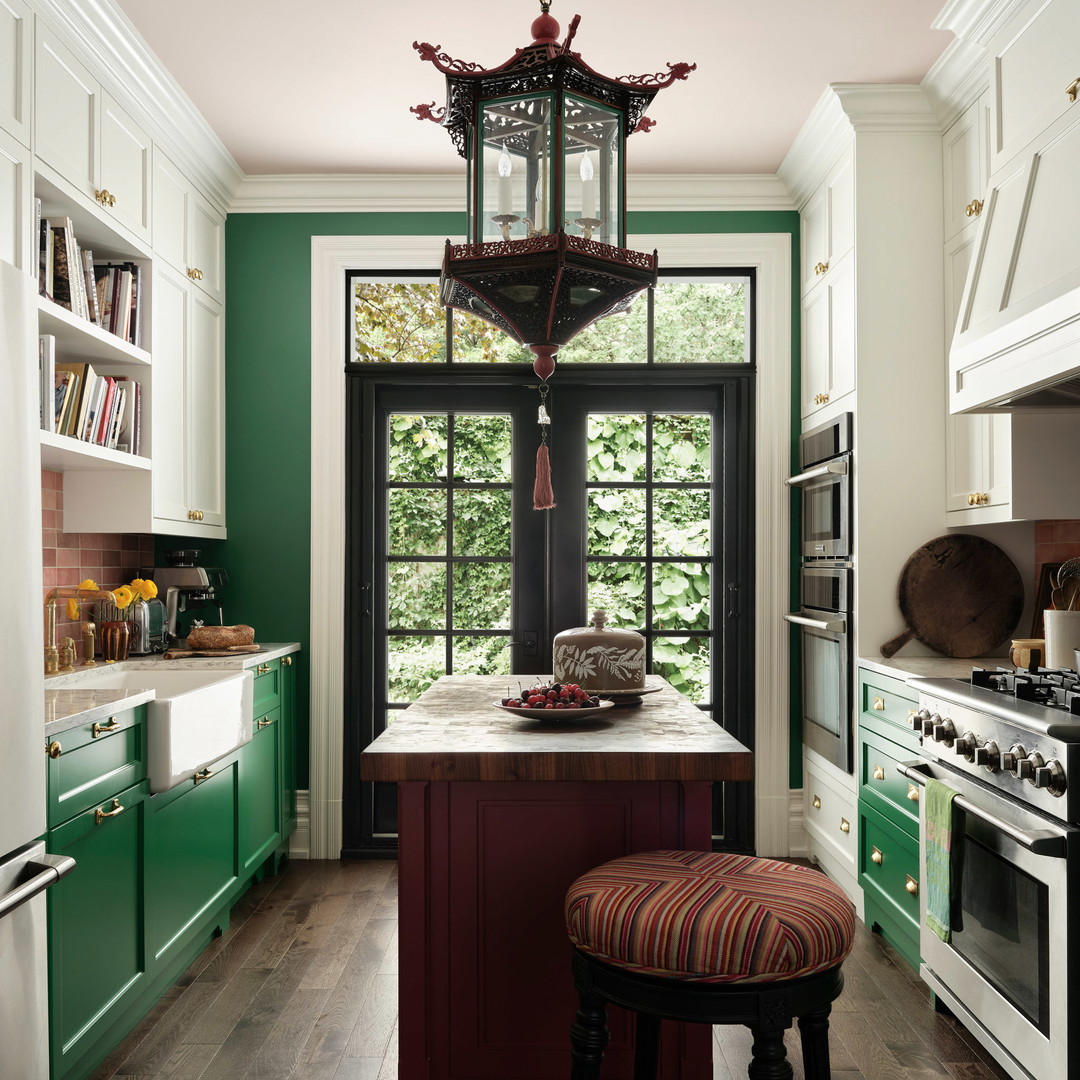 a kitchen with green cabinets and a red stool