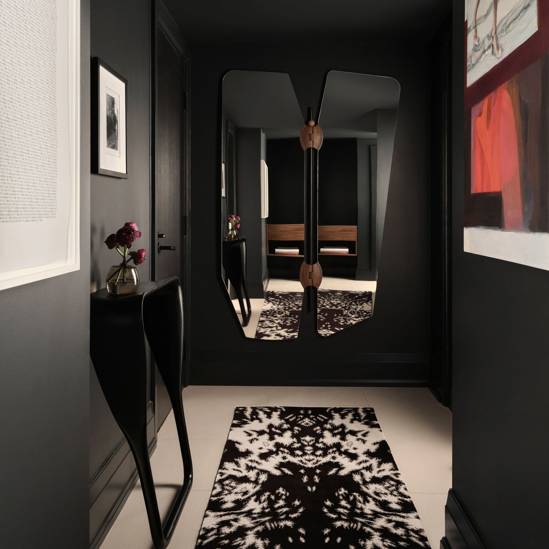 a black and white hallway with a mirror and a chair