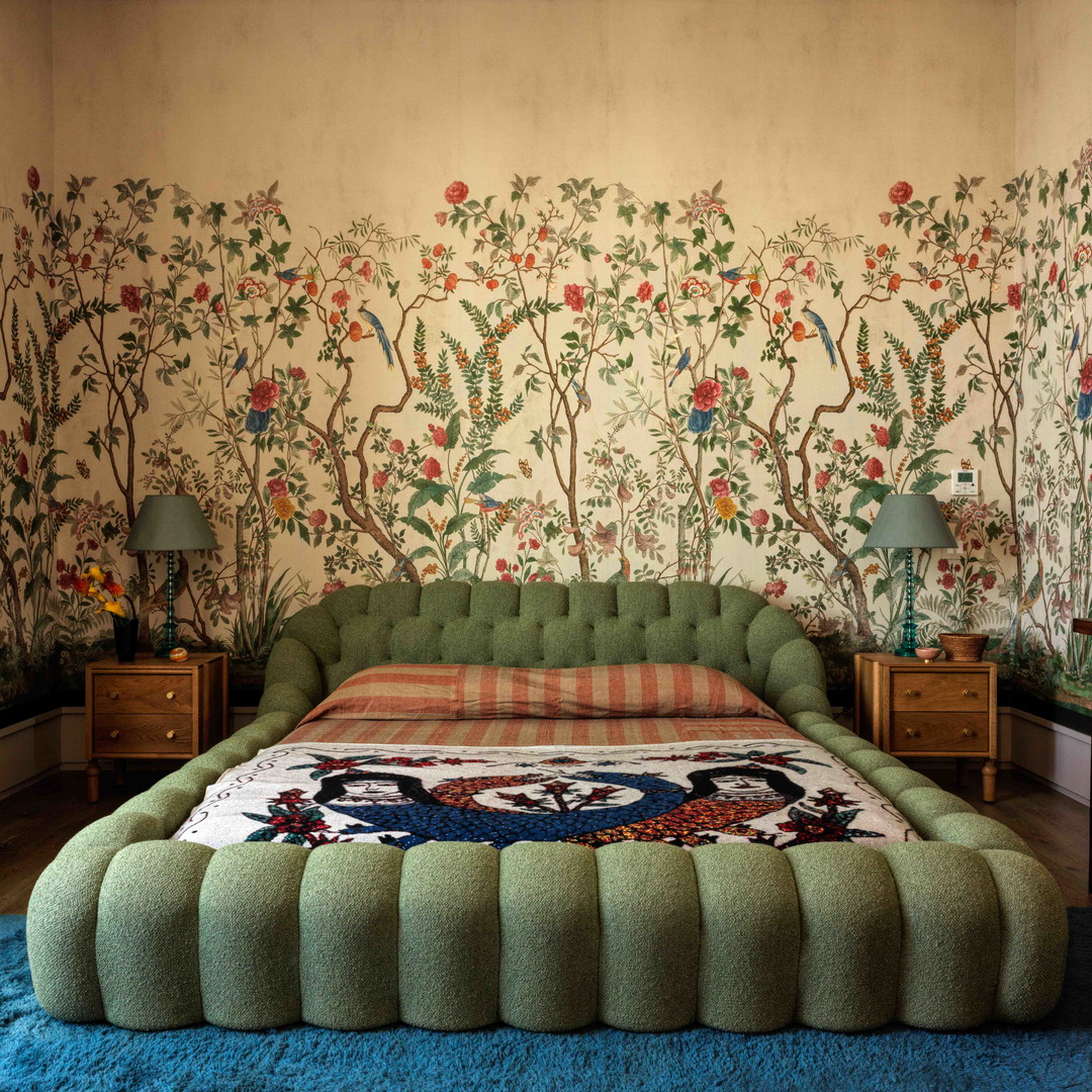 a bedroom with a green bed and floral wallpaper