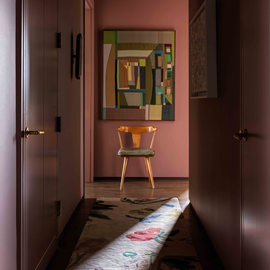 a hallway with a chair and a painting on the wall