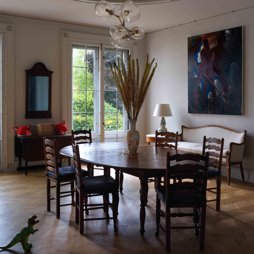 a dining room table with chairs and a painting on the wall