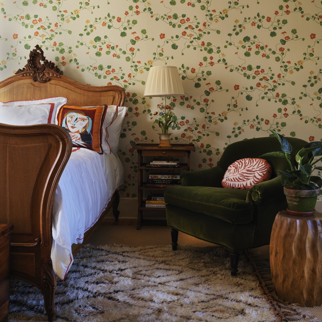 a bedroom with a green chair and a floral wallpaper