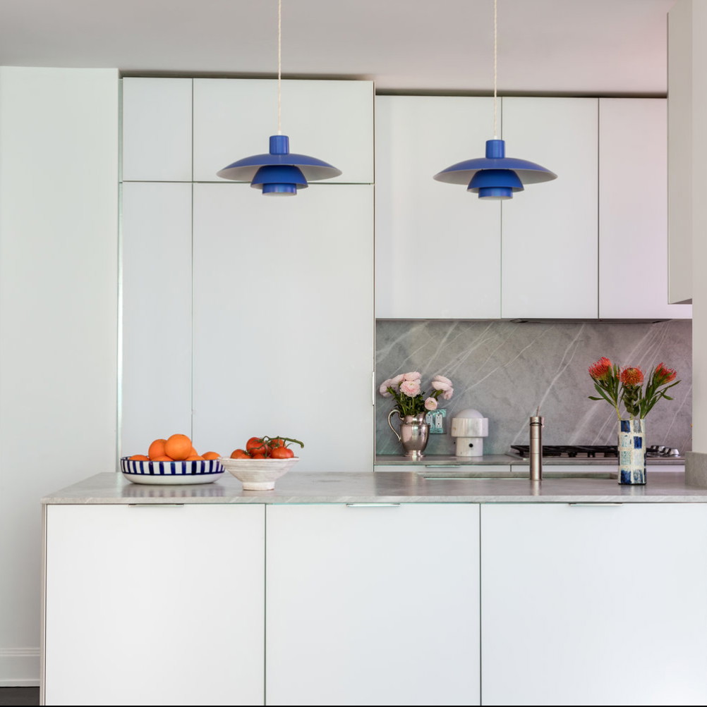 a kitchen with white cabinets and blue pendant lights