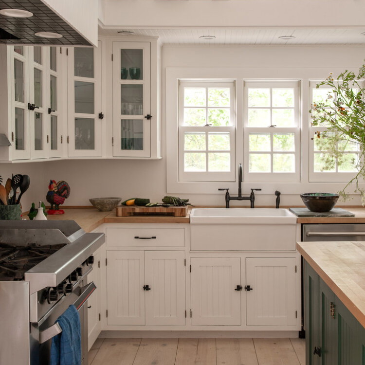 a kitchen with a stove, sink, cabinets and a window