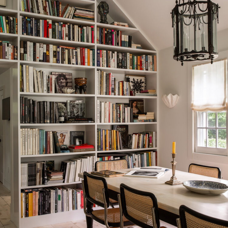 a dining room table and chairs in front of a bookshelf