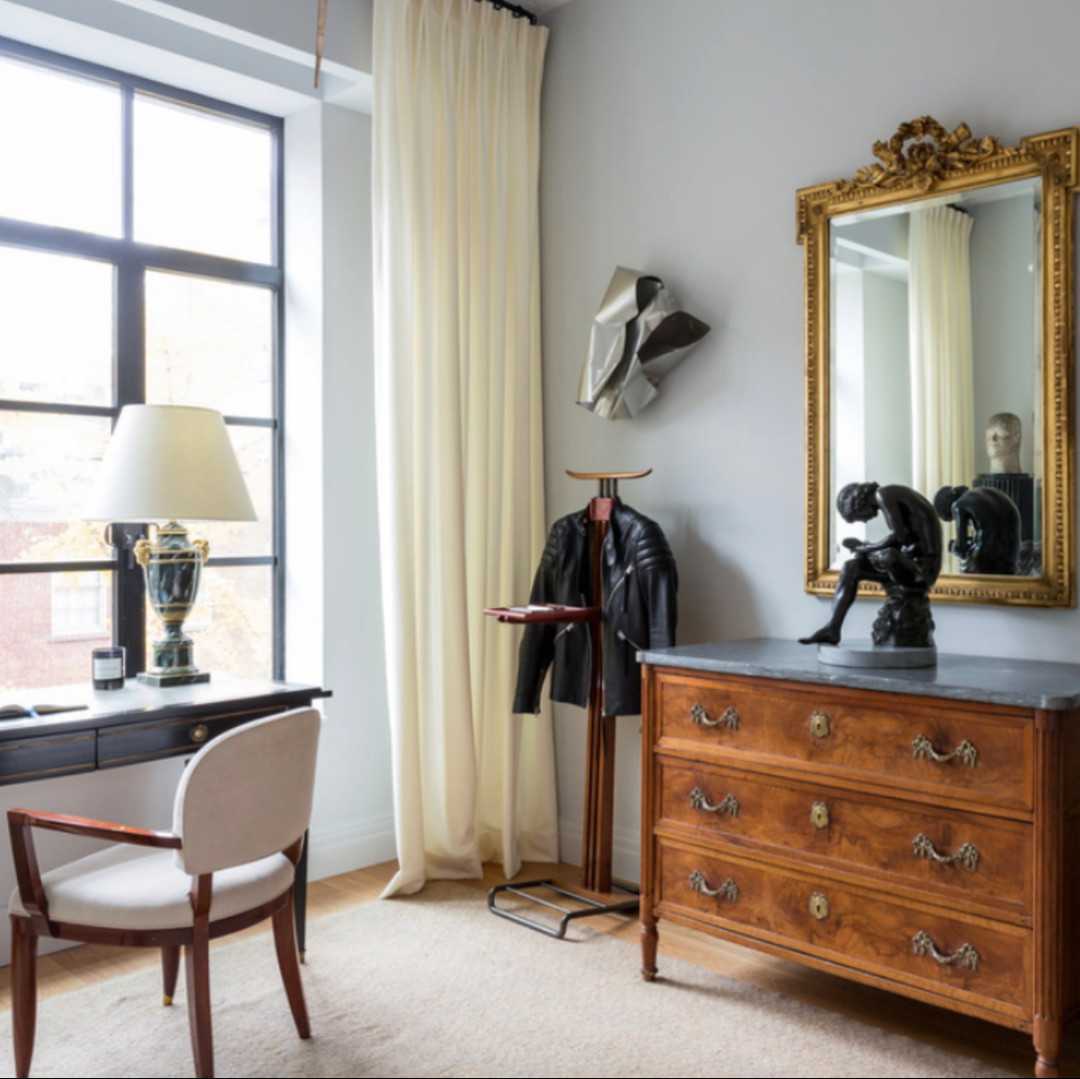 a room with a dresser, mirror and a chair