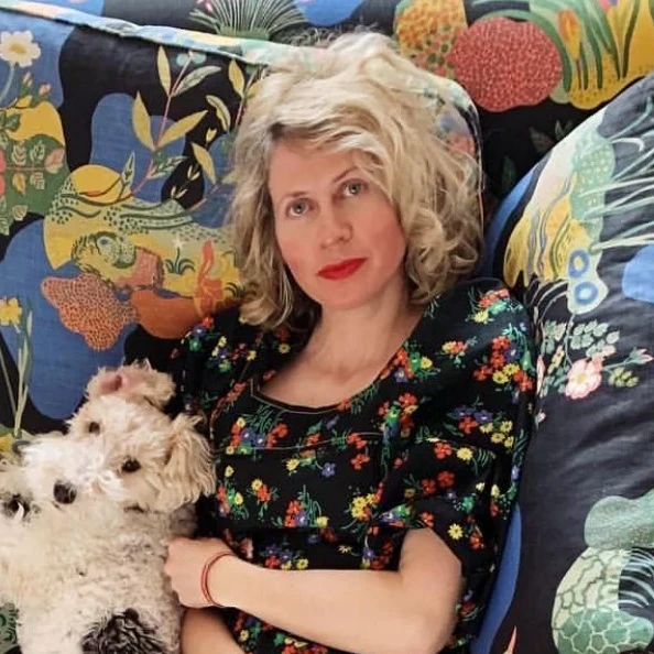 a woman sitting on a couch holding a white dog