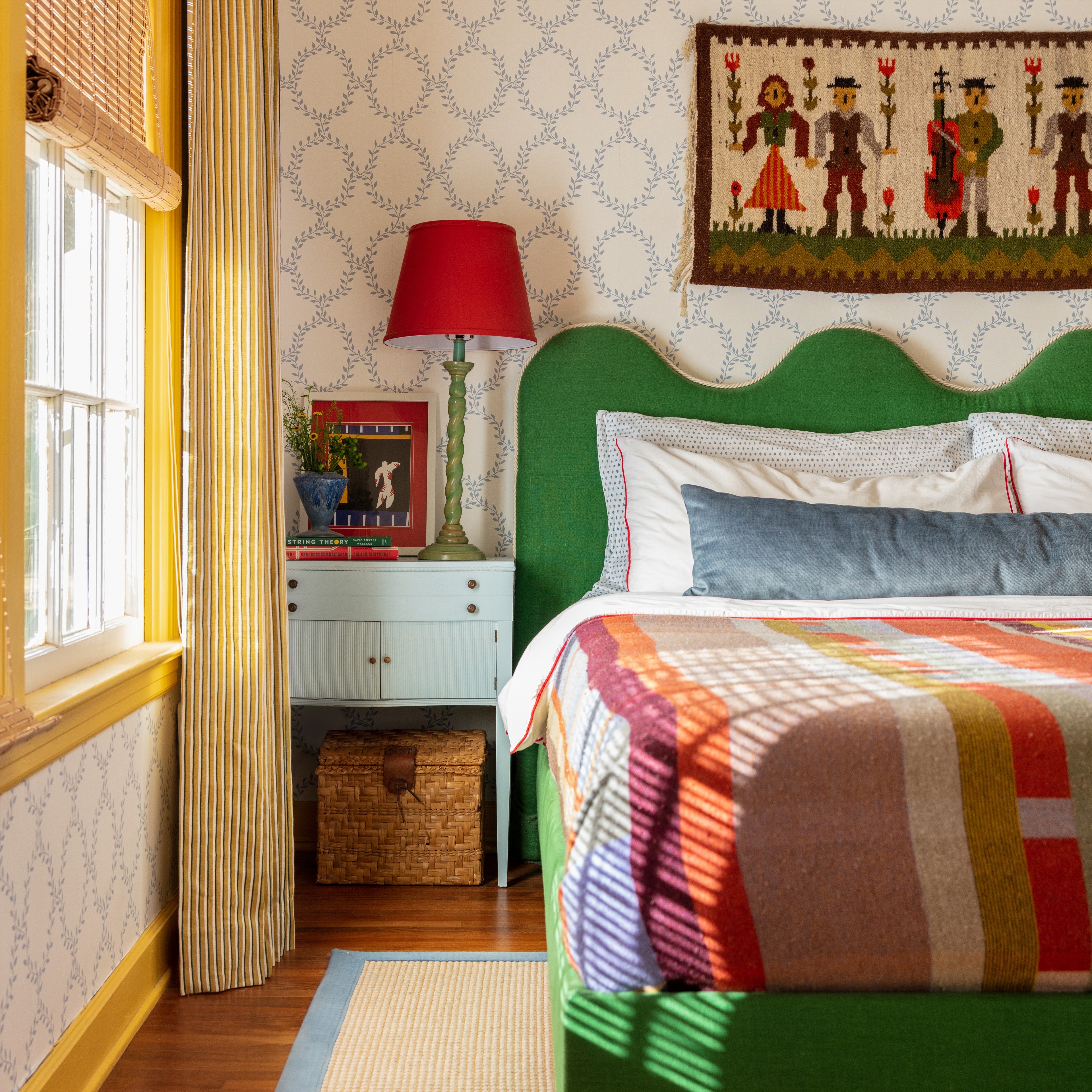 a bedroom with a green headboard and a red lamp