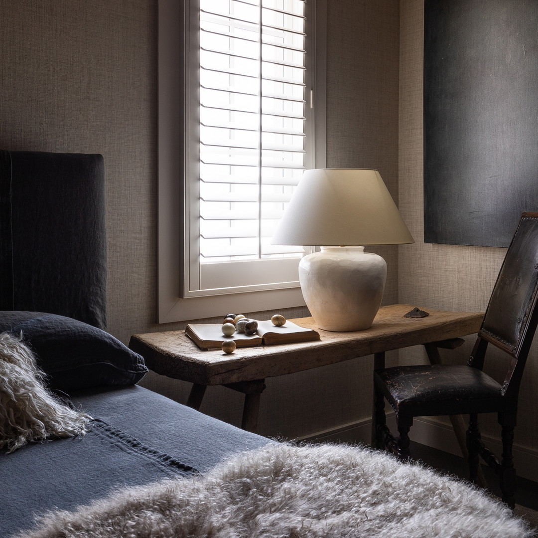 a bedroom with a bed, chair, table and window