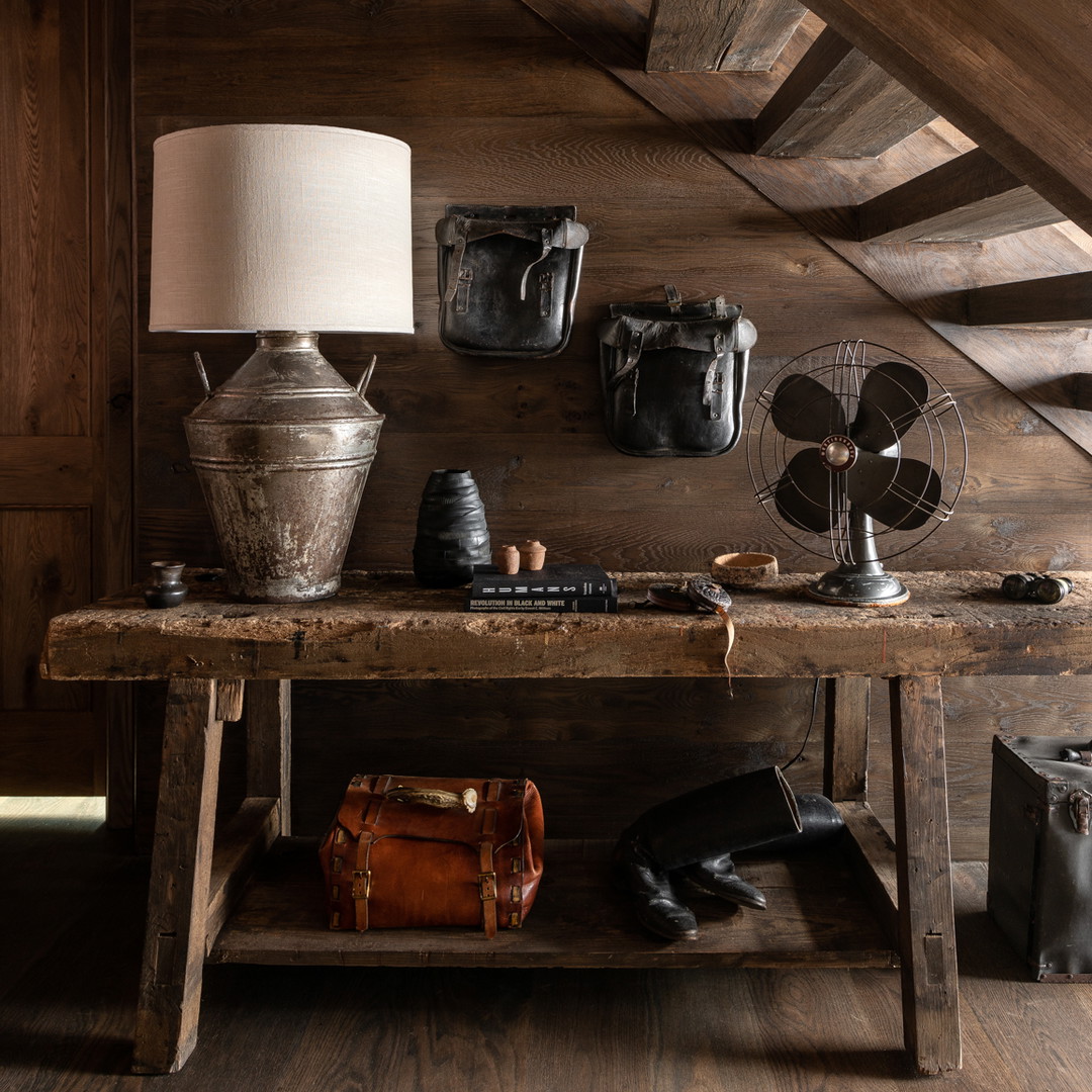 a wooden table topped with a lamp next to a wooden staircase