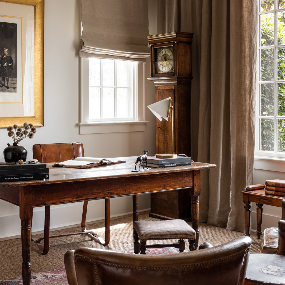 a room with a desk, chair, clock and window