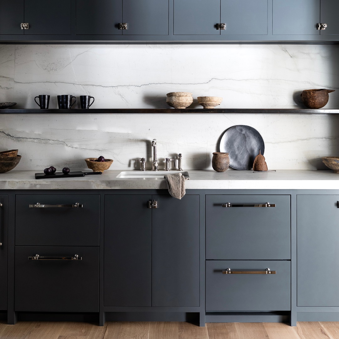 a kitchen with gray cabinets and marble counter tops