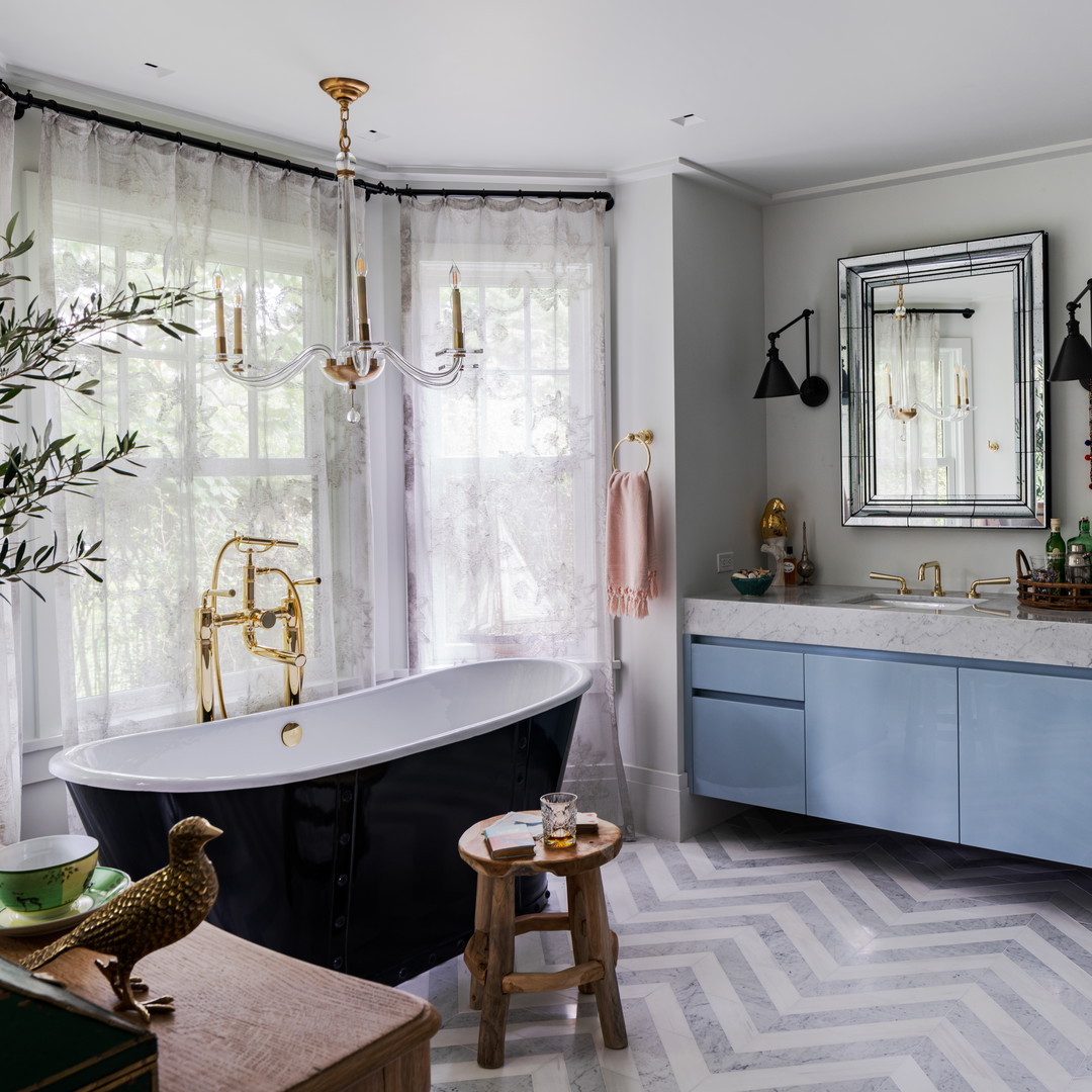 a bathroom with a bathtub, sink, mirror, and stool